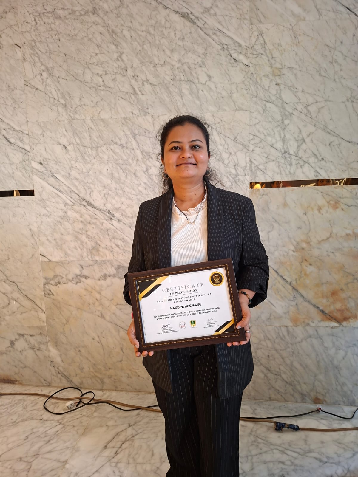 Nandini holding the Intensive Health Coach Certificate of Participation, Ahmedabad, July 2026